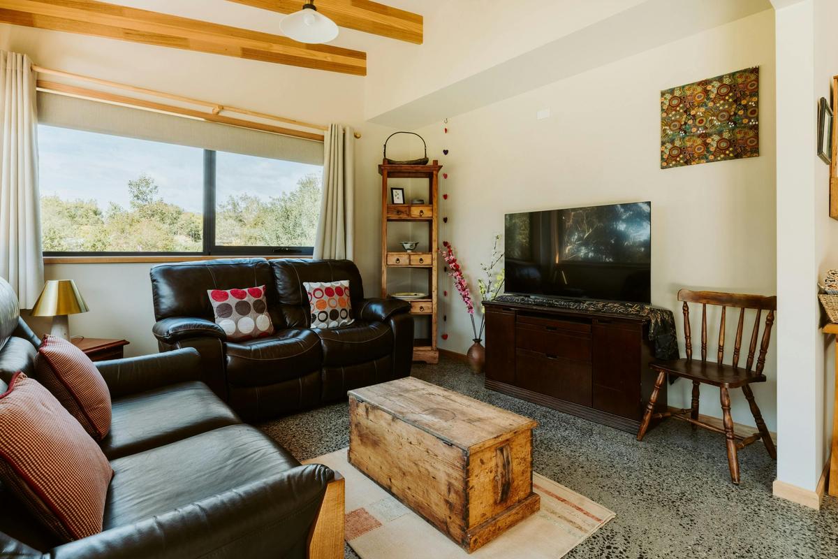 The living space features comfortable leather couches and a Smart TV.