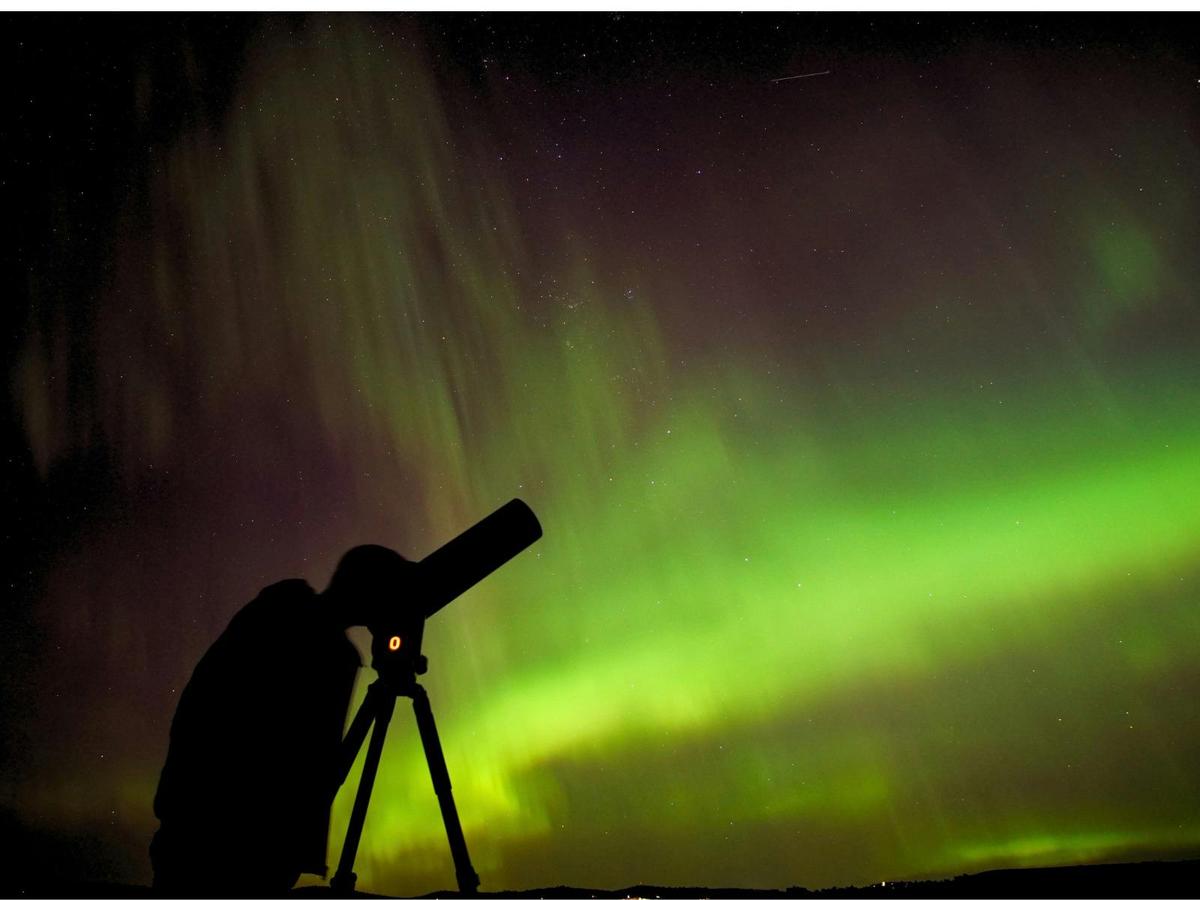 Guest looking through a telescope as the aurora glows across Tasmania’s night sky.