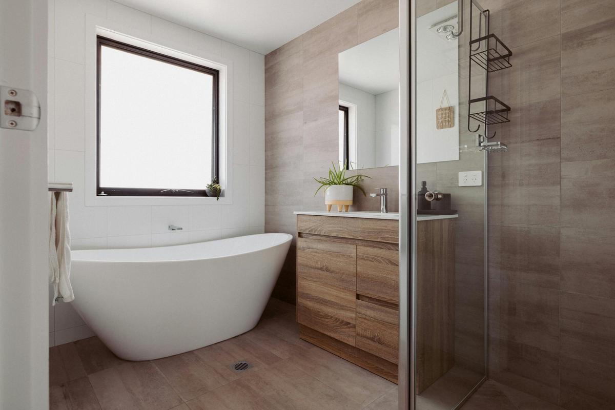 Modern bathroom with bathtub and shower, equipped with a hair dryer and supplied toiletries.