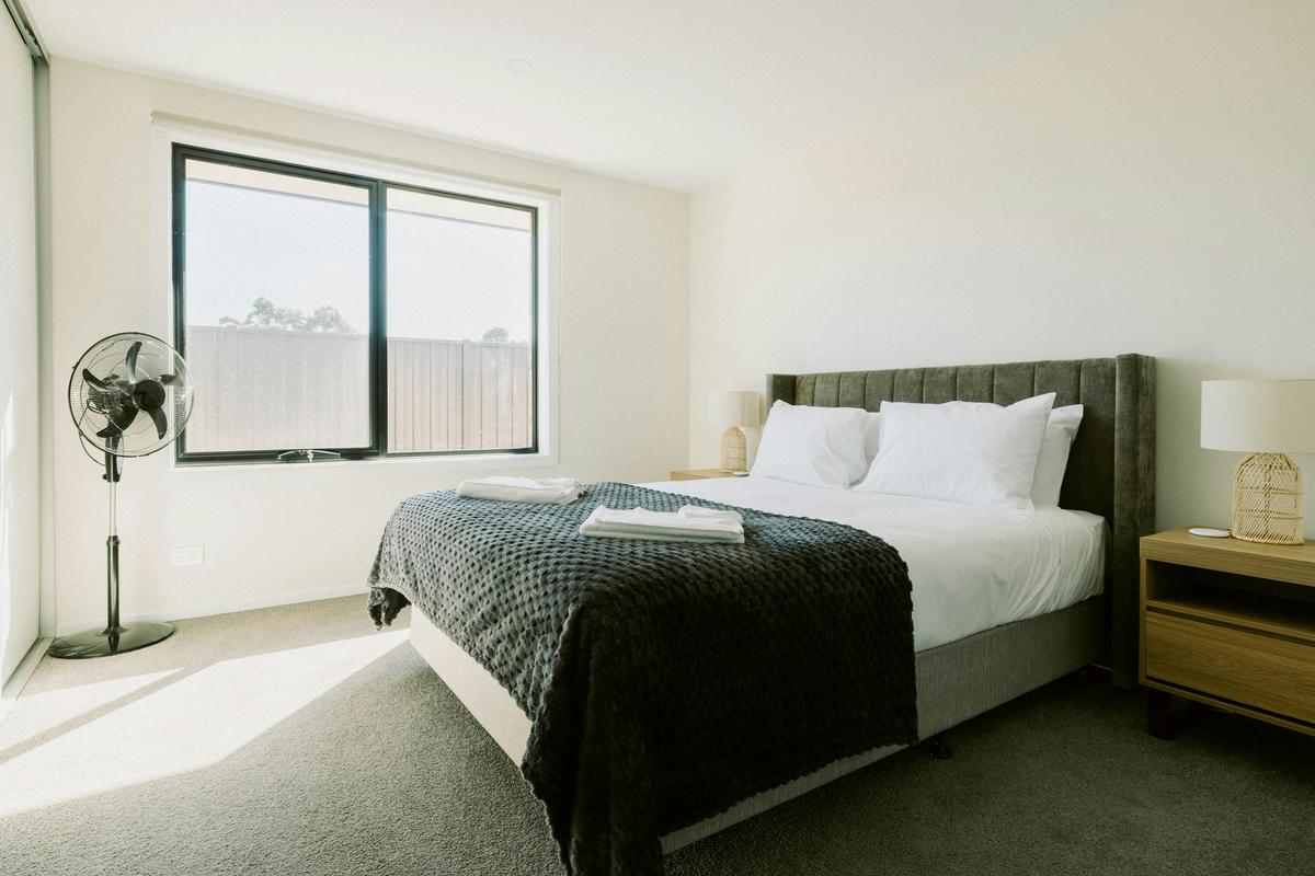 The master bedroom features a queen bed, ensuite, modern furnishings, and bedside charging pads.