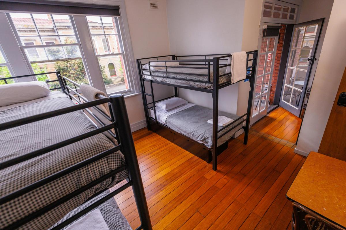 Several bunk beds in room with wooden floorboards at YHA Hobart Central
