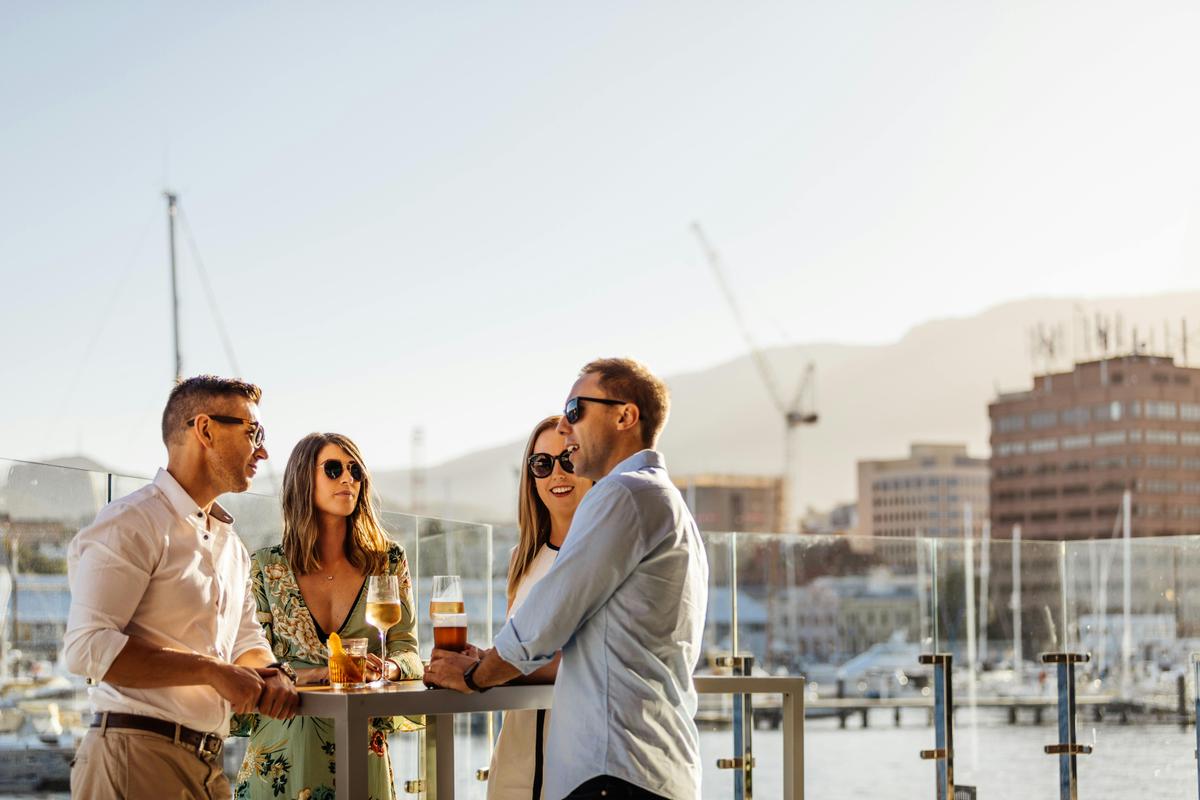 Four guests on the deck at The Story Bar on a sunny day with Mt Wellington in the background