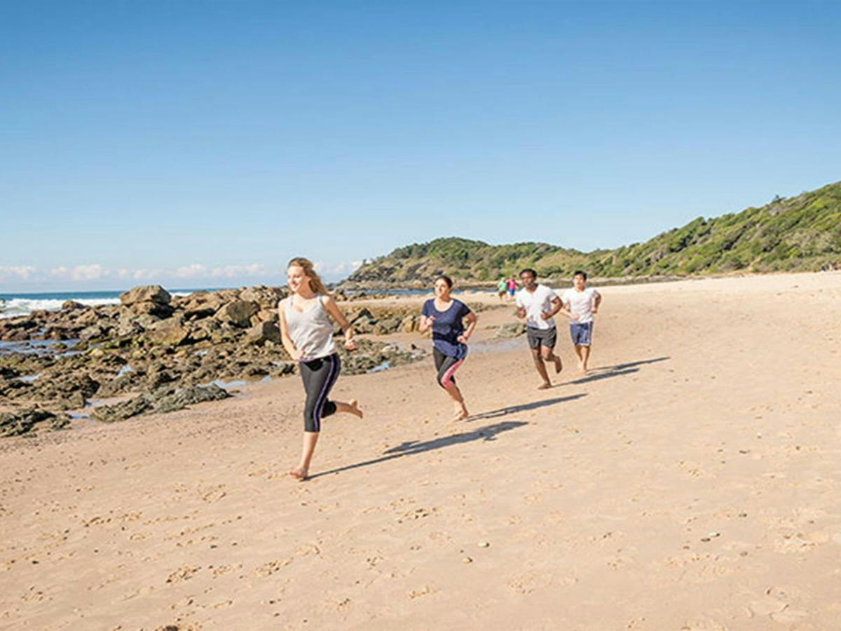 A group of people exercising on the beach along the Port Macquarie coastal walk in Sea Acres