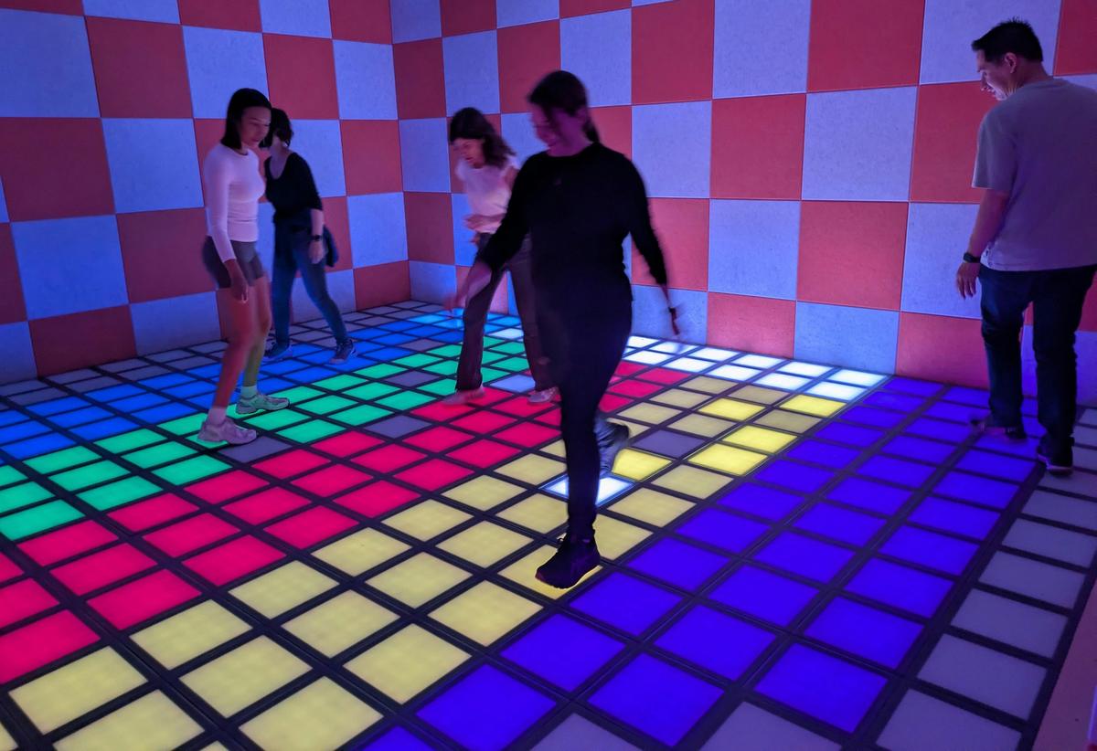 Players on a floor with coloured interactive tiles