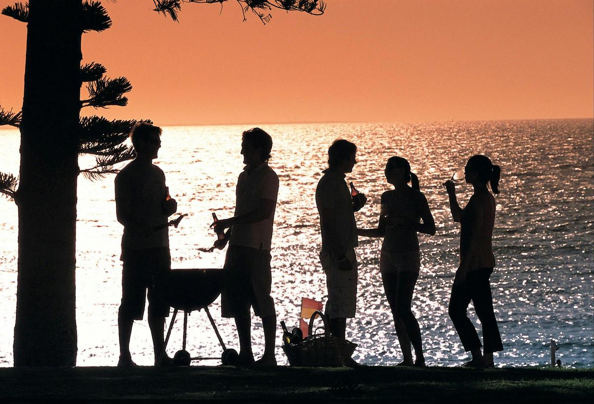 Group enjoying a barbecue at Cottesloe Beach at sunset