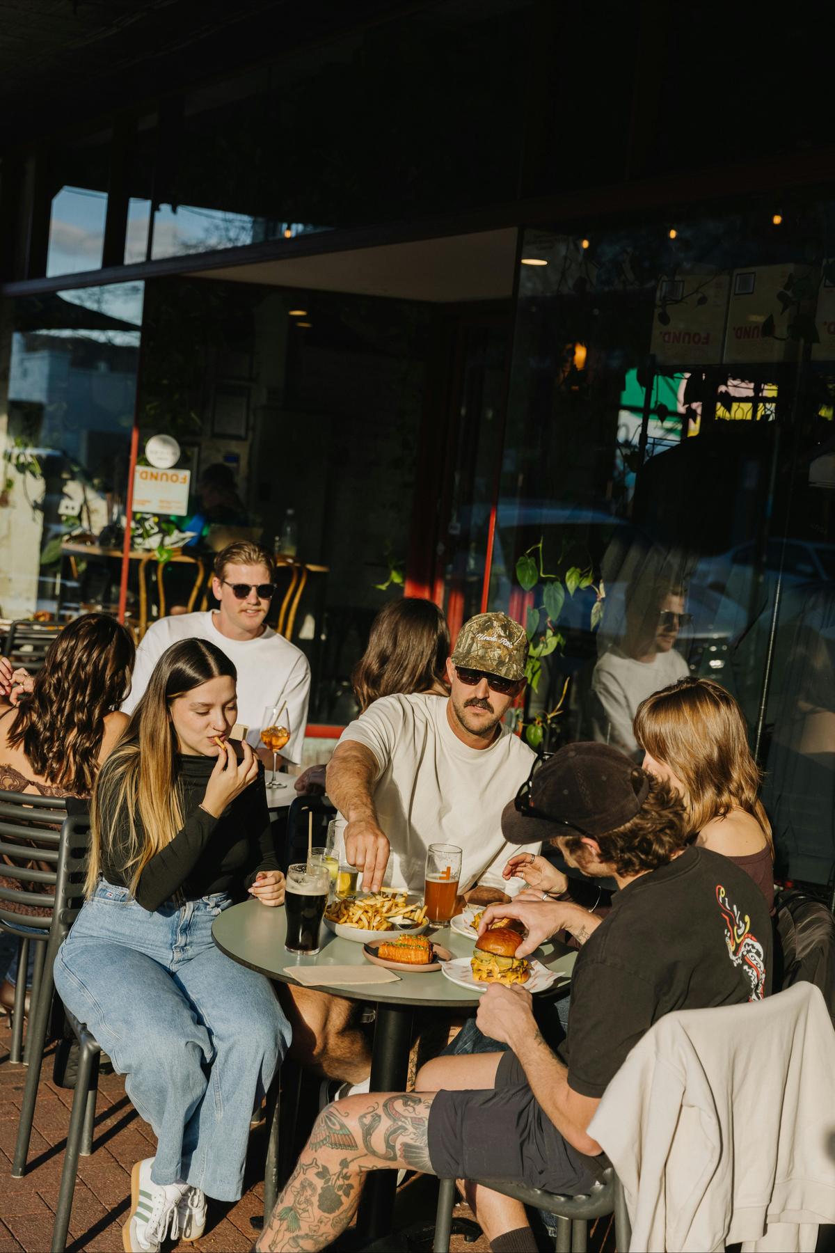 Group of friends eating and drinking at an outdoor table at Found Subiaco