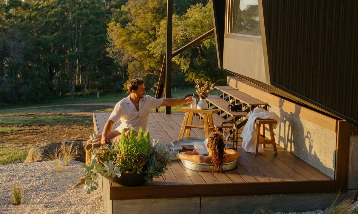 Woman in outdoor bath with man sat on the deck