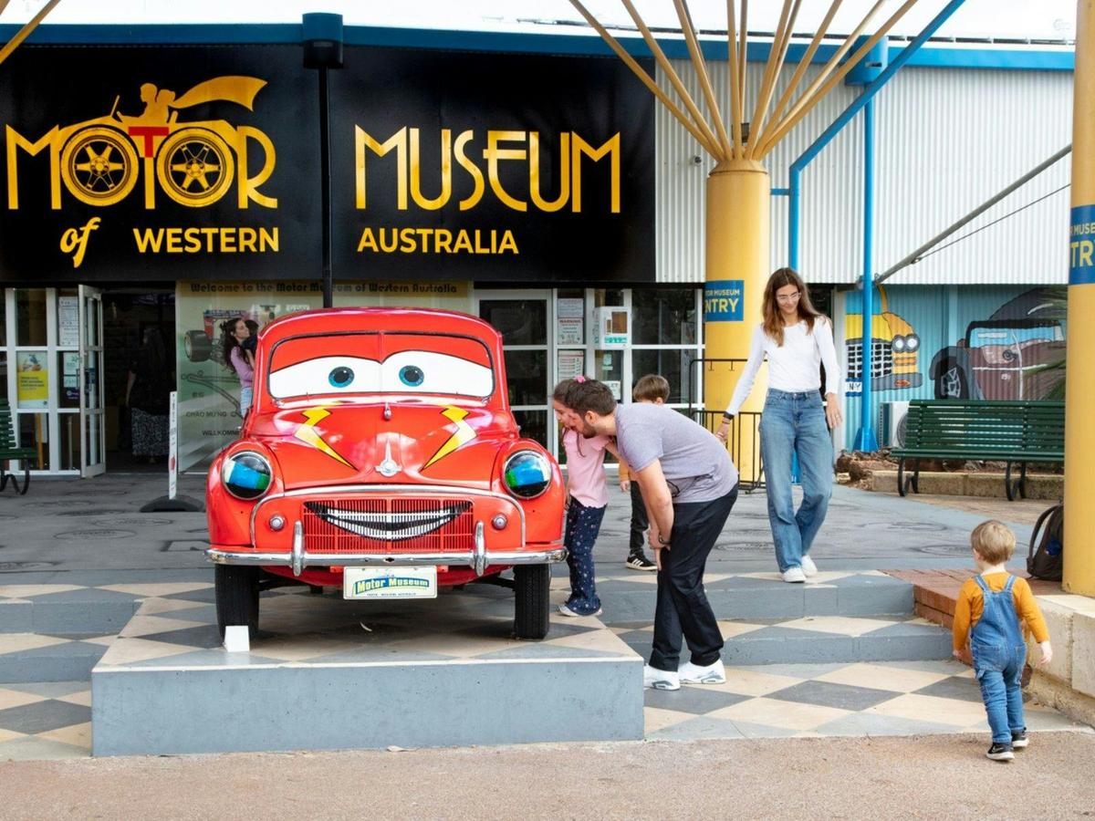 Families out the front of Motor Museum of Western Australia admiring the red Morris Minor