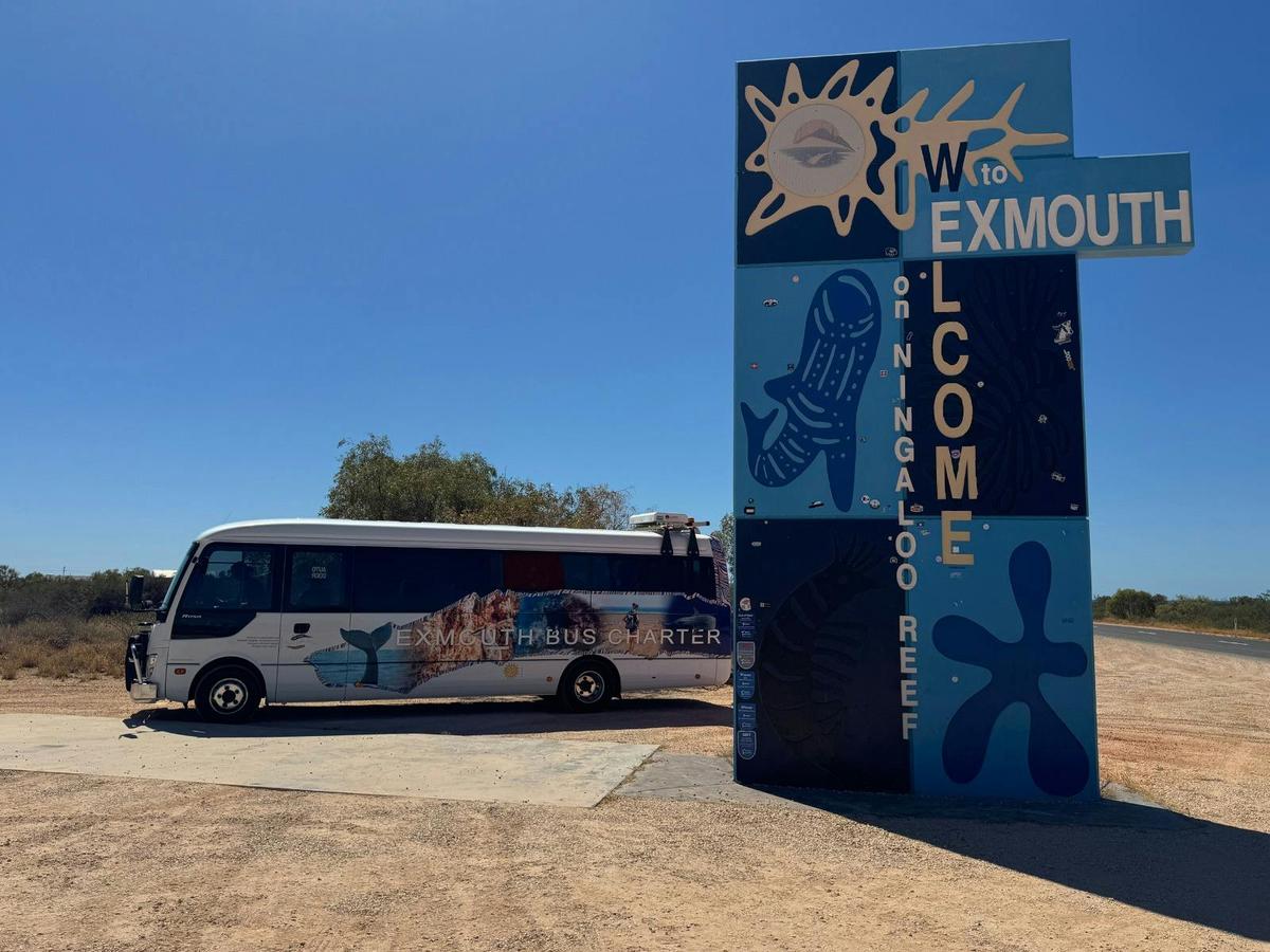 Exmouth Bus Charter bus at the iconic Exmouth town sign, welcoming visitors to the region.