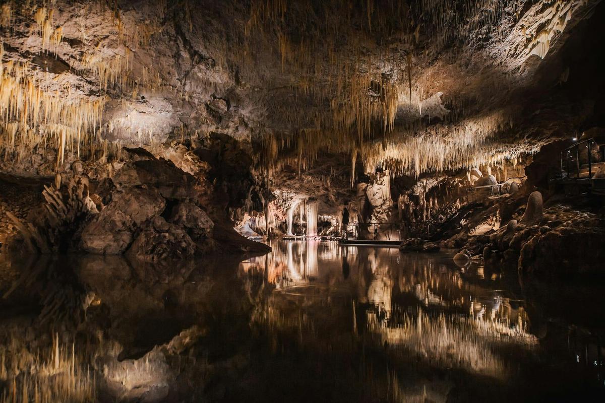 A tranquil lake reflects the delicate crystal formations that grow from the cave ceiling.