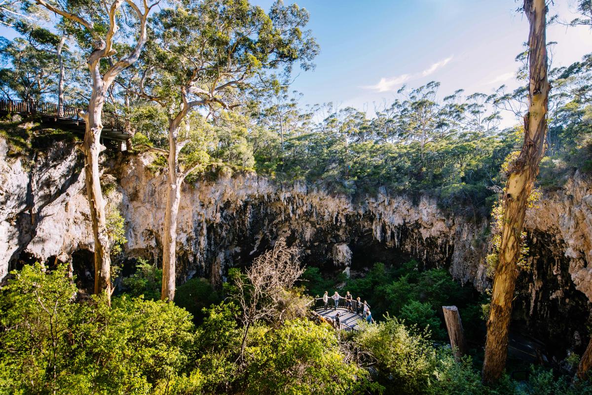 Visitors descend a staircase into a spectacular ancient sinkhole before entering Lake Cave.