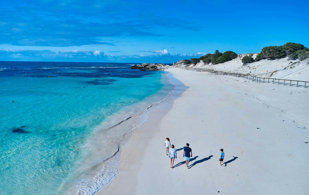 Aerial photo of a family walking on a white sandy beach.