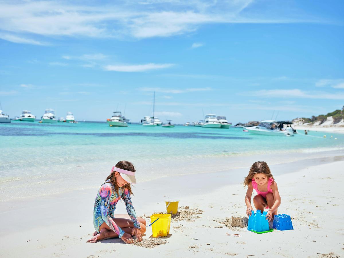Two young girls building sandcastles at the water's edge.