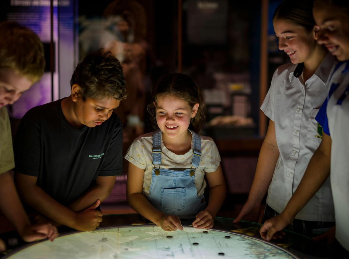A group of young people and children look at an illuminated display
