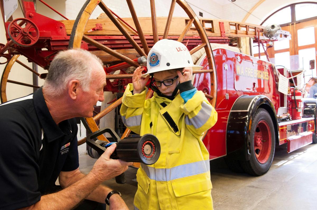 Retired firefighter showing a junior firefighter how to operate a fire hose