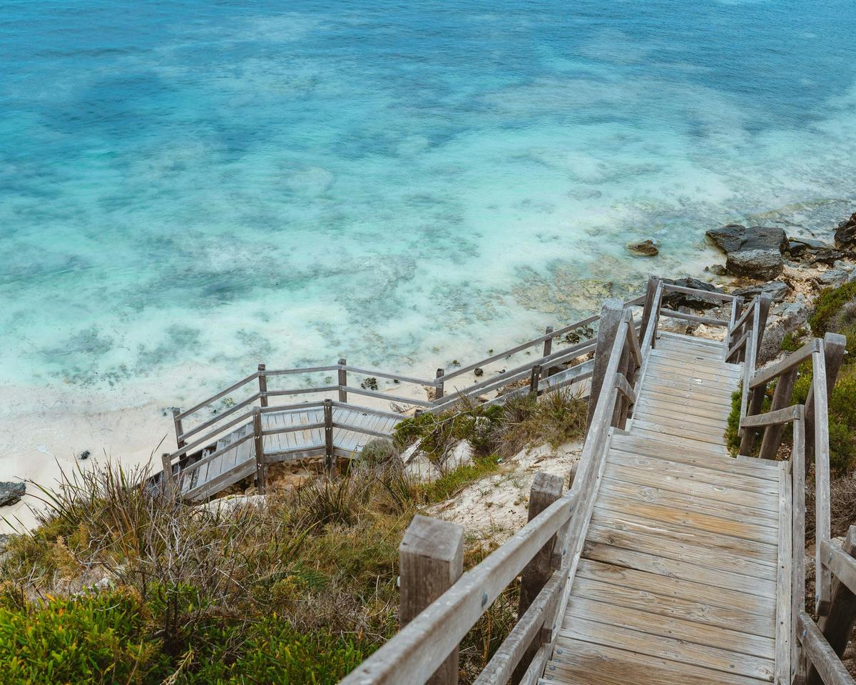 View from top of staircase down to blue waters and white sand