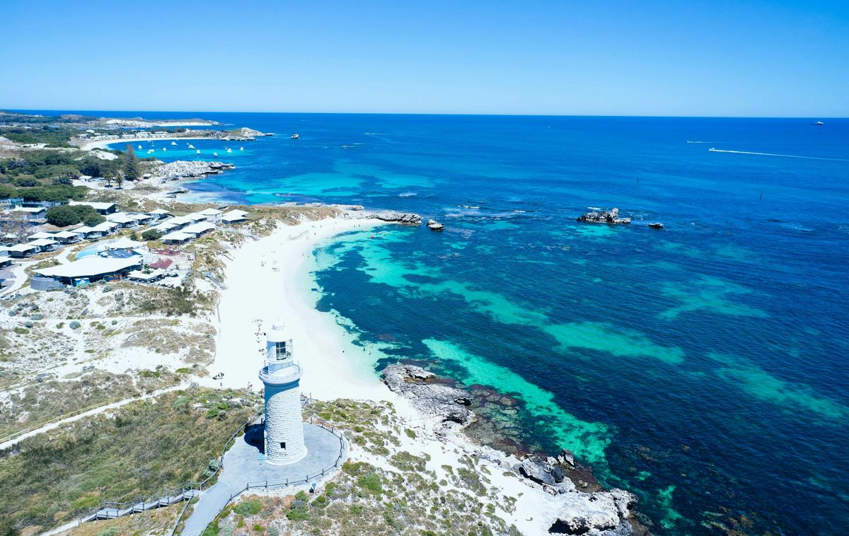 Aerial view of white sandy beach and historic lighthouse.