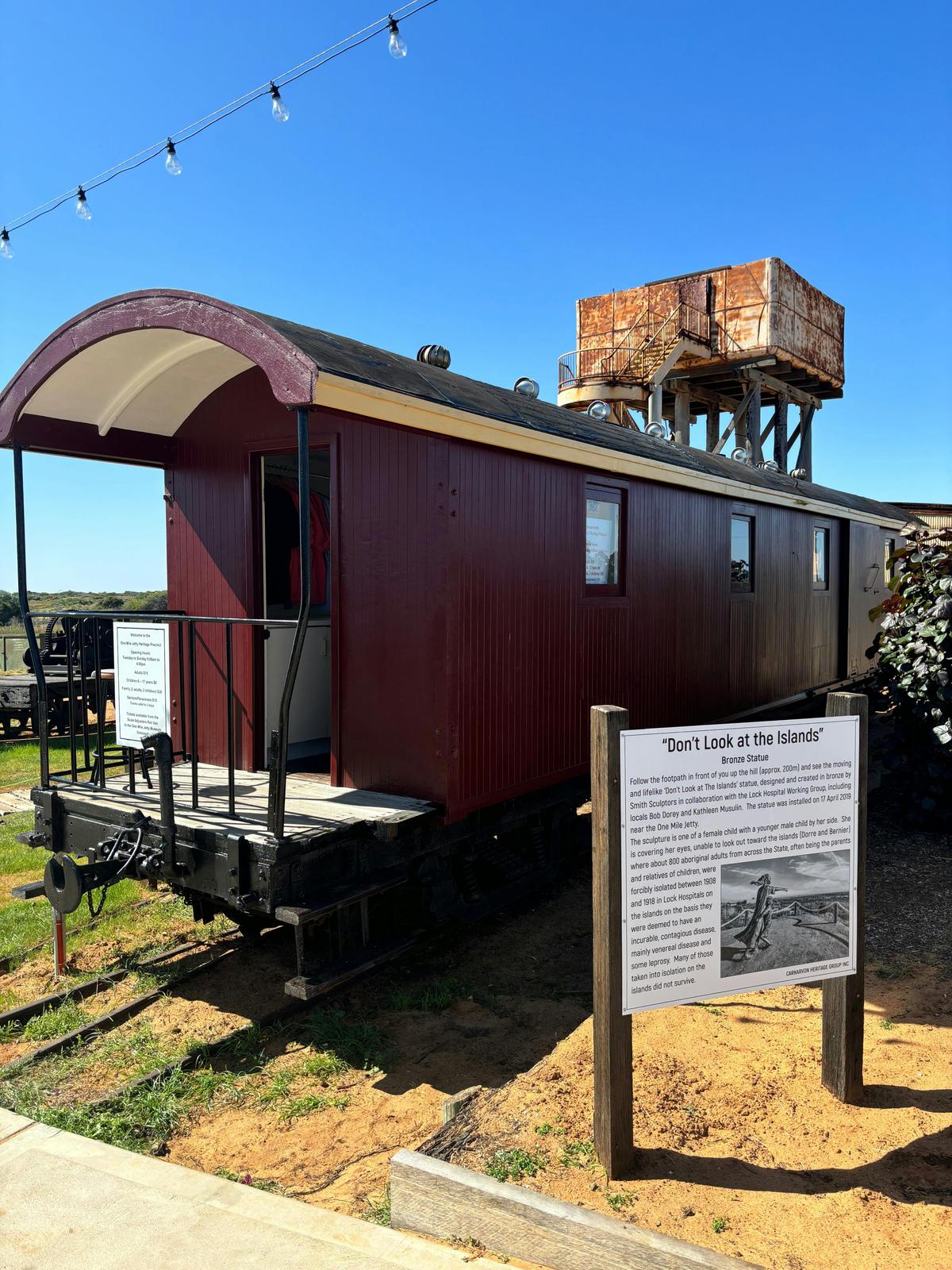 Scale adjusters van/ ticket office with description of "Don't Look at Me" statue and old water tank