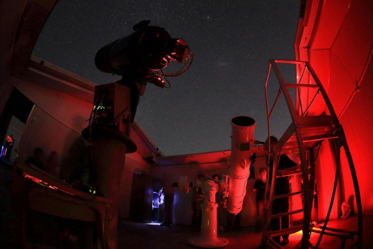A person looking through the Claver Telescope on a Night Sky Tour