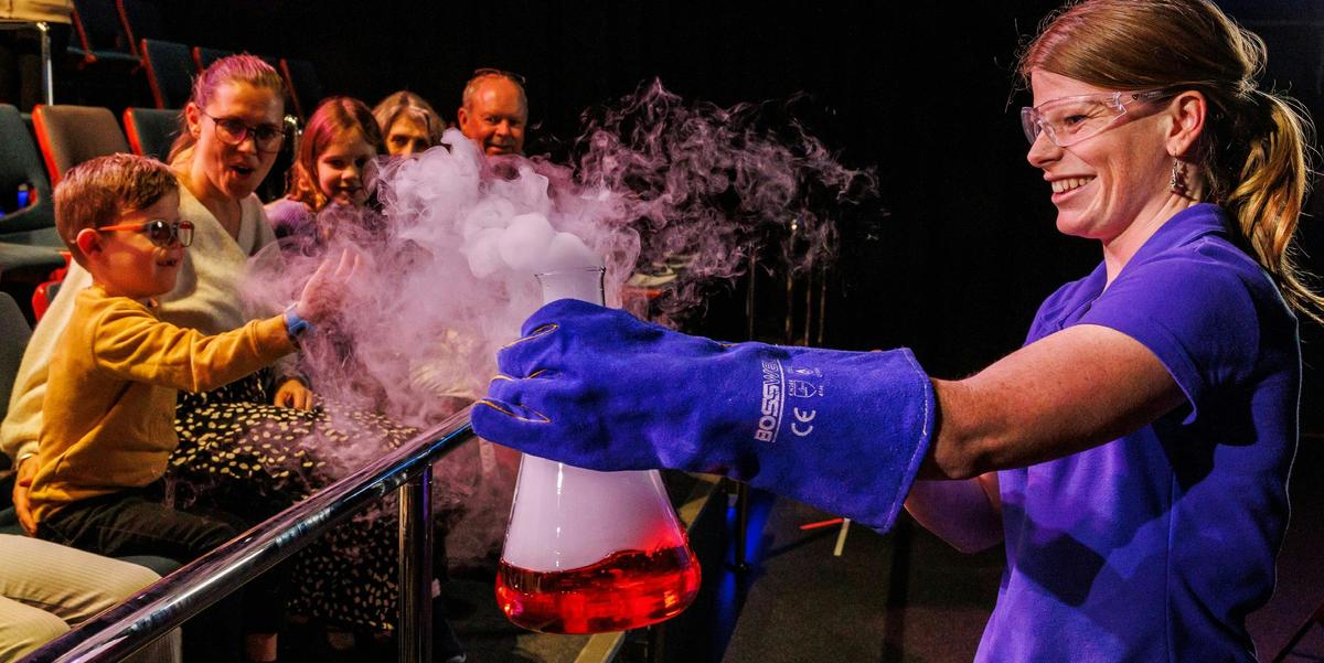 Scitech Presenter holding beaker to crowd in a live science theatre show