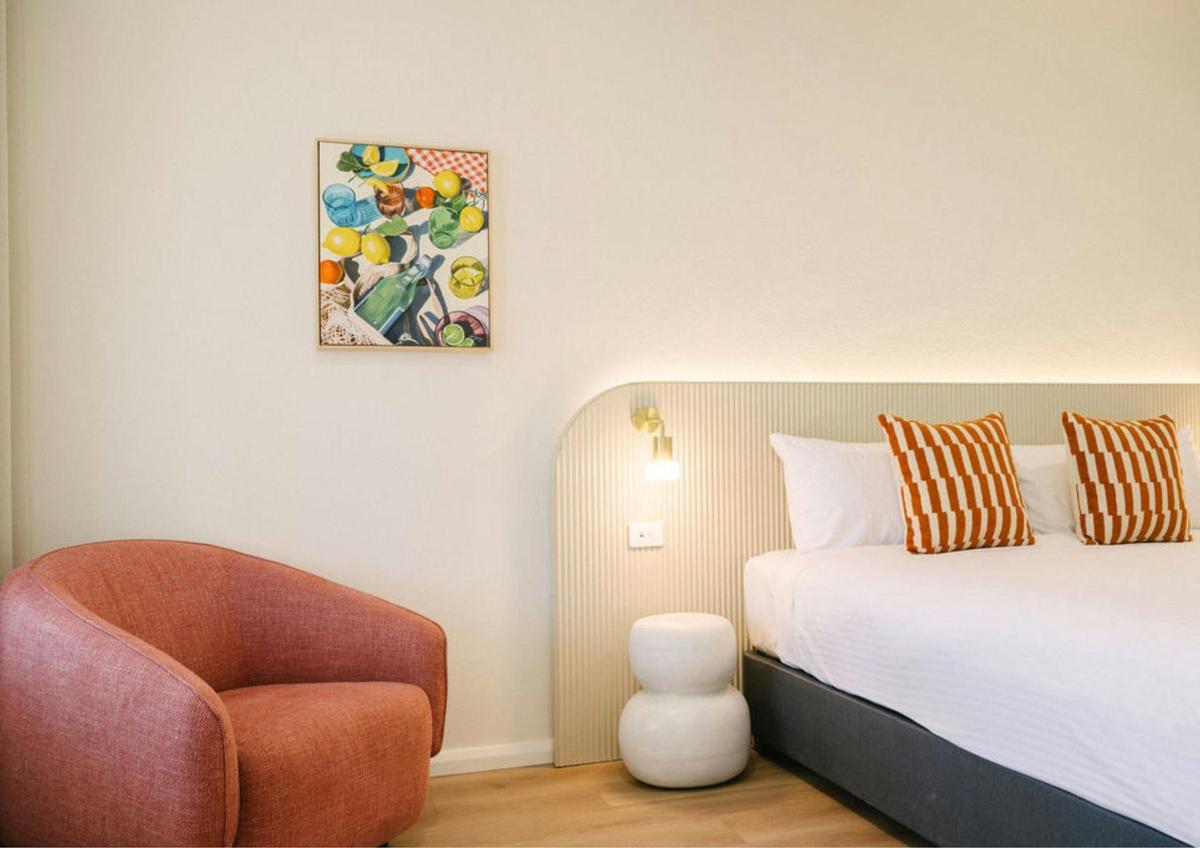 Bedroom with custom artwork, lounge chairs, king bed and premium bedding