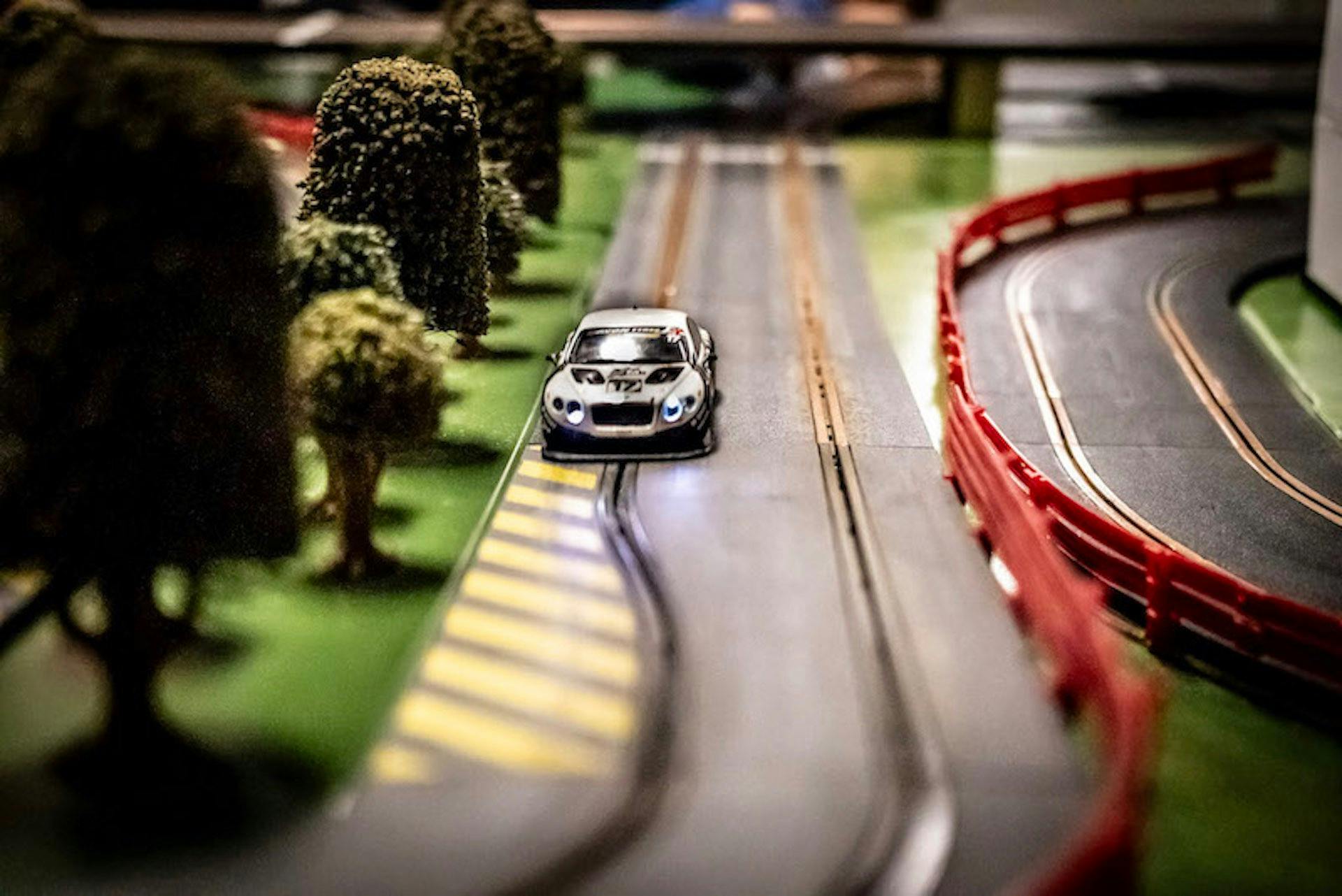 Close-up of a slot car speeding down the track past miniature trees.