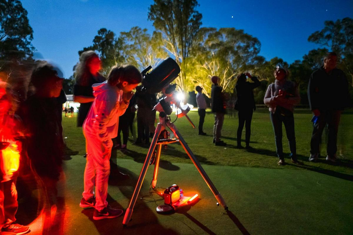 Young girl looking into telescope at Chittering event.