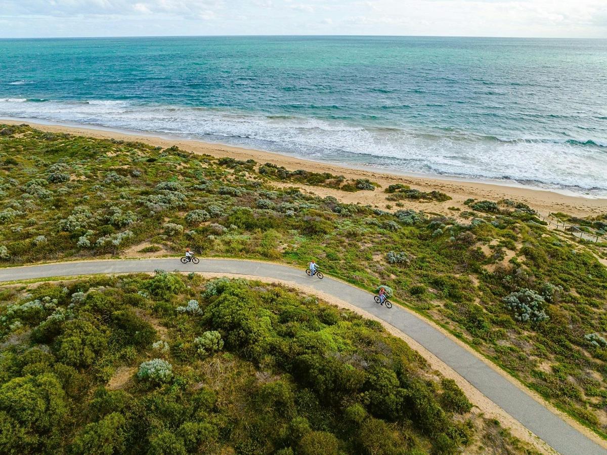 Cyclists round the coastal bend at Halls Head on a guided mandurah e-bike adventure