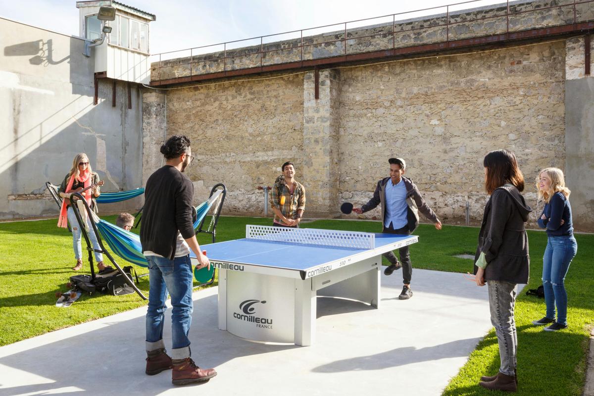 Guests playing table tennis outdoors in prison courtyard