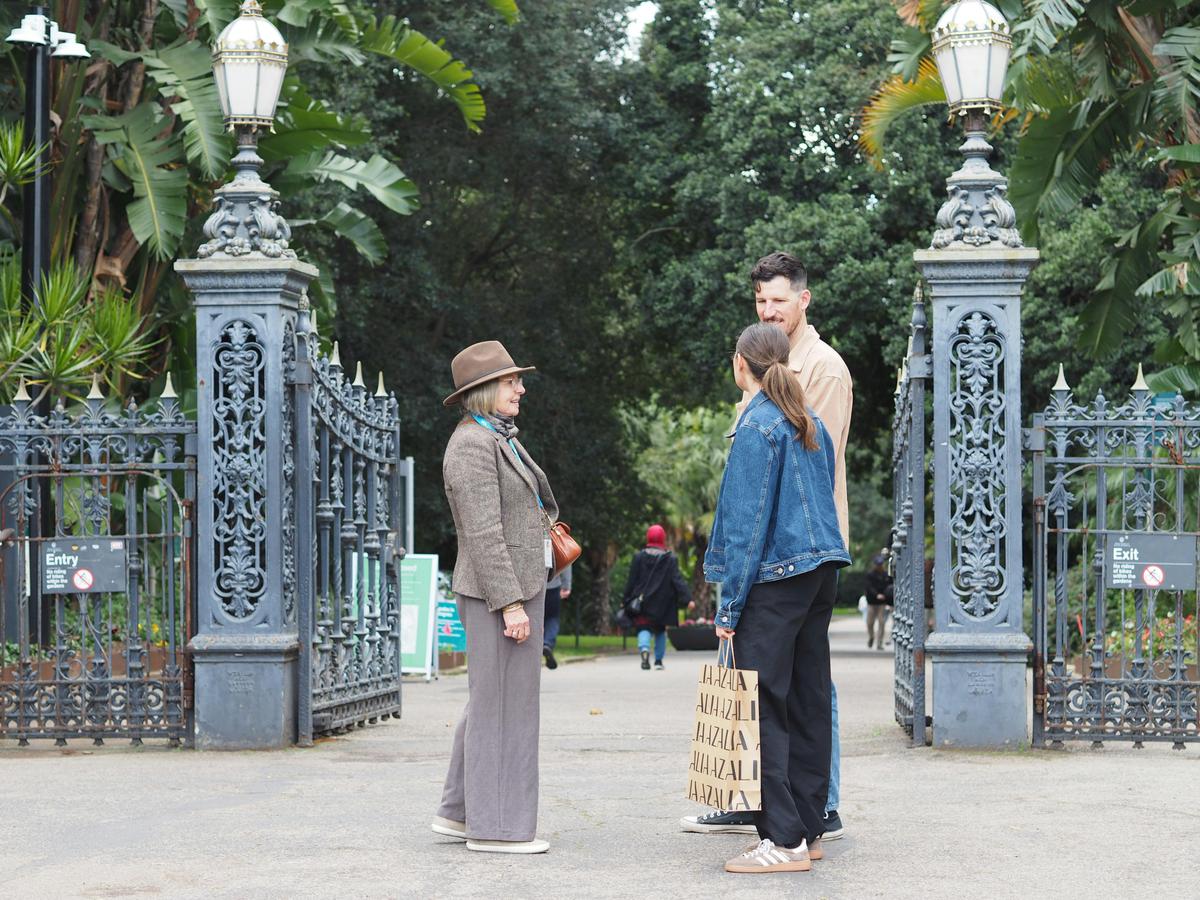 A guide is talking to two people outside the entrance to the Botanic Gardens