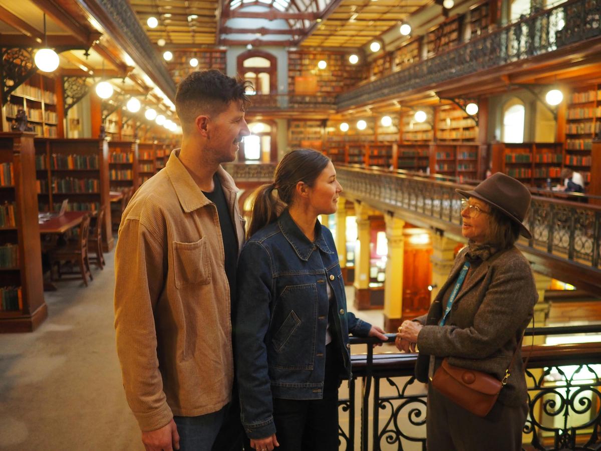 A guide is talking to two people inside an old library