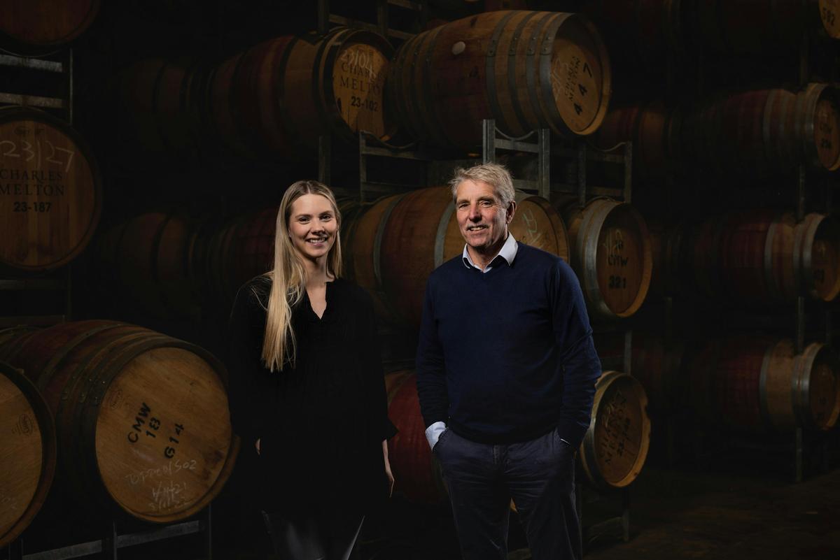 A female and male standing in front of barrels