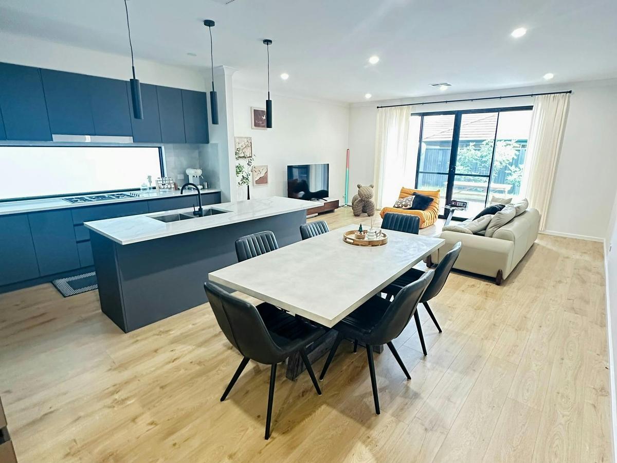 Open‑plan kitchen and dining area with a dining table, chairs and pendant lights.