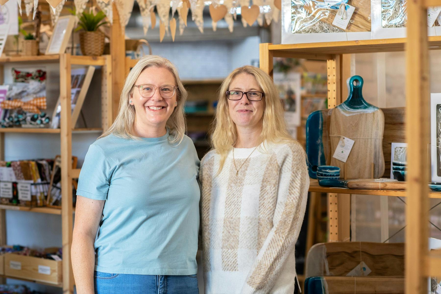 Two blonde women wearing glasses smiling in a store