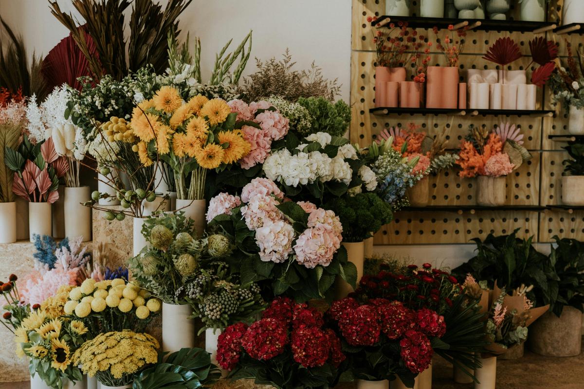 Fresh flower stand with colourful blooms and retail shelves with vases and dried arrangements
