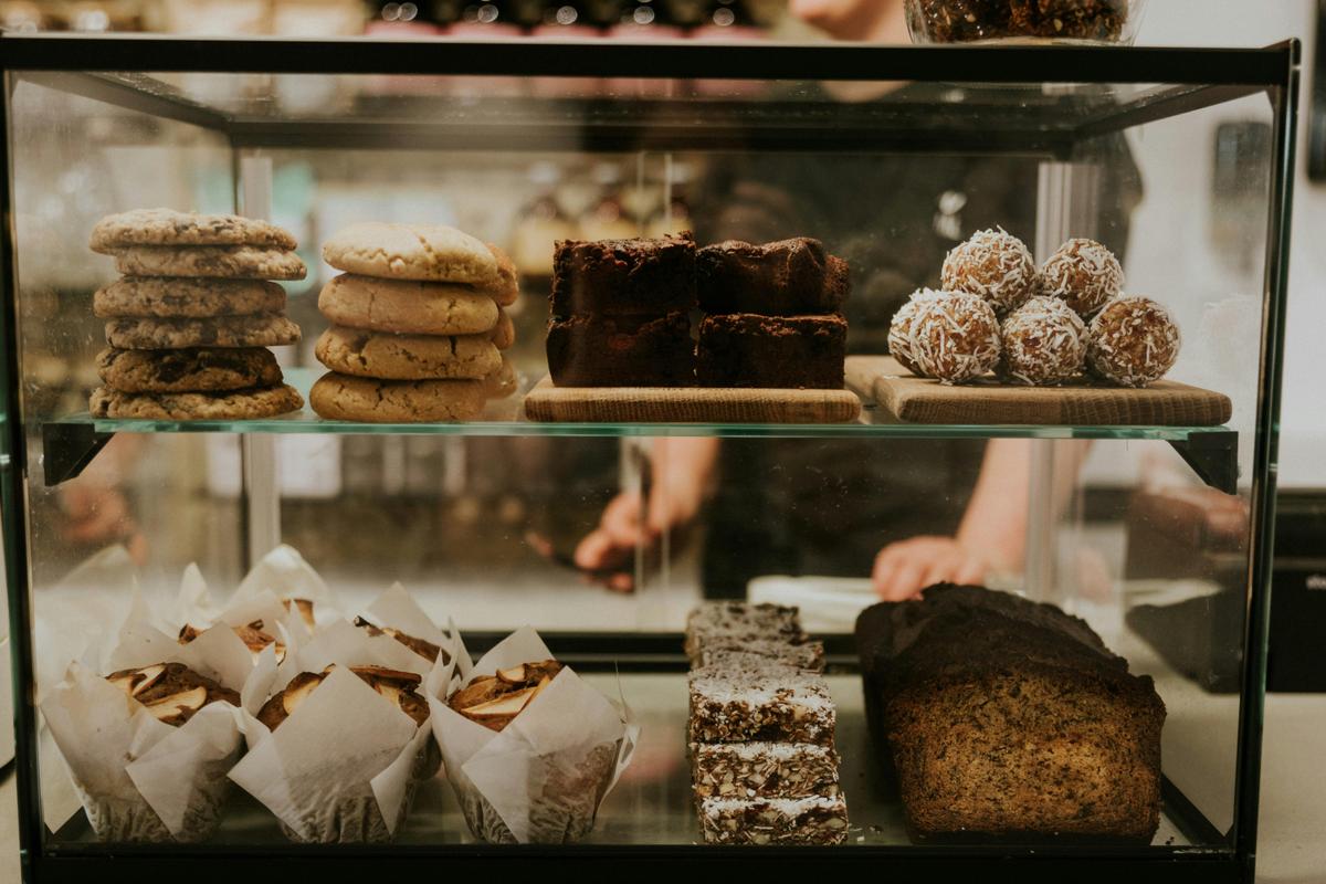 Glass pastry case loaded with cookies, muffins, banana bread, muesli bars