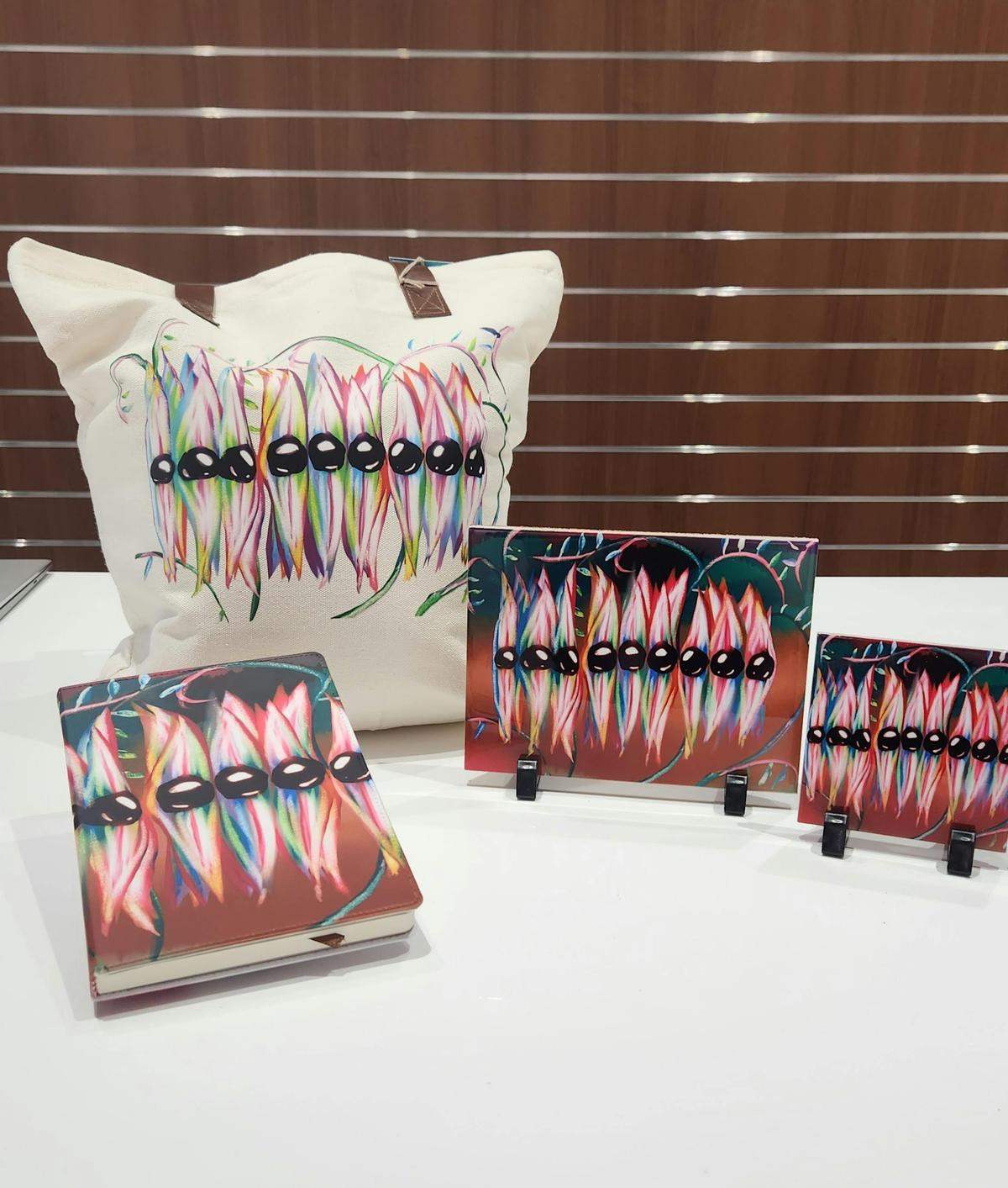 Grace's design of Sturt's Desert Peas on different products, including tote bags, tiles and journal.