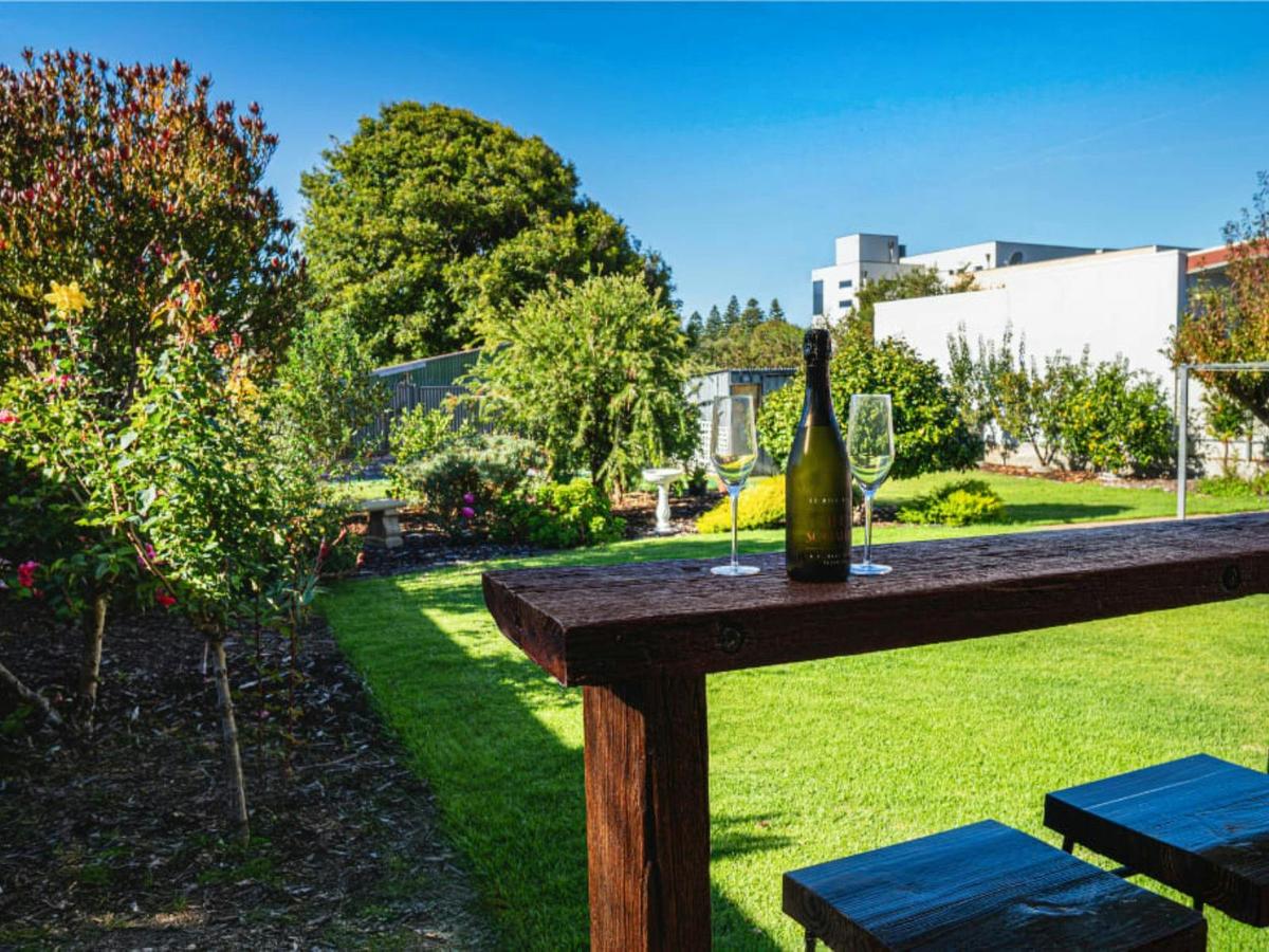 Courtyard at Grantley Retreat with garden views, outdoor seating and wine glasses on a timber table.