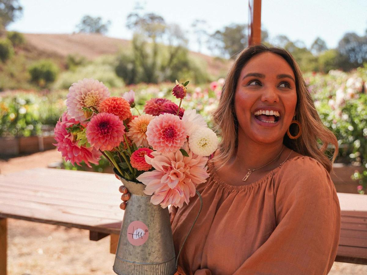 Visitor holding a vibrant bouquet of dahlias at sunny Hahndorf Flower Farm in the Adelaide Hills.