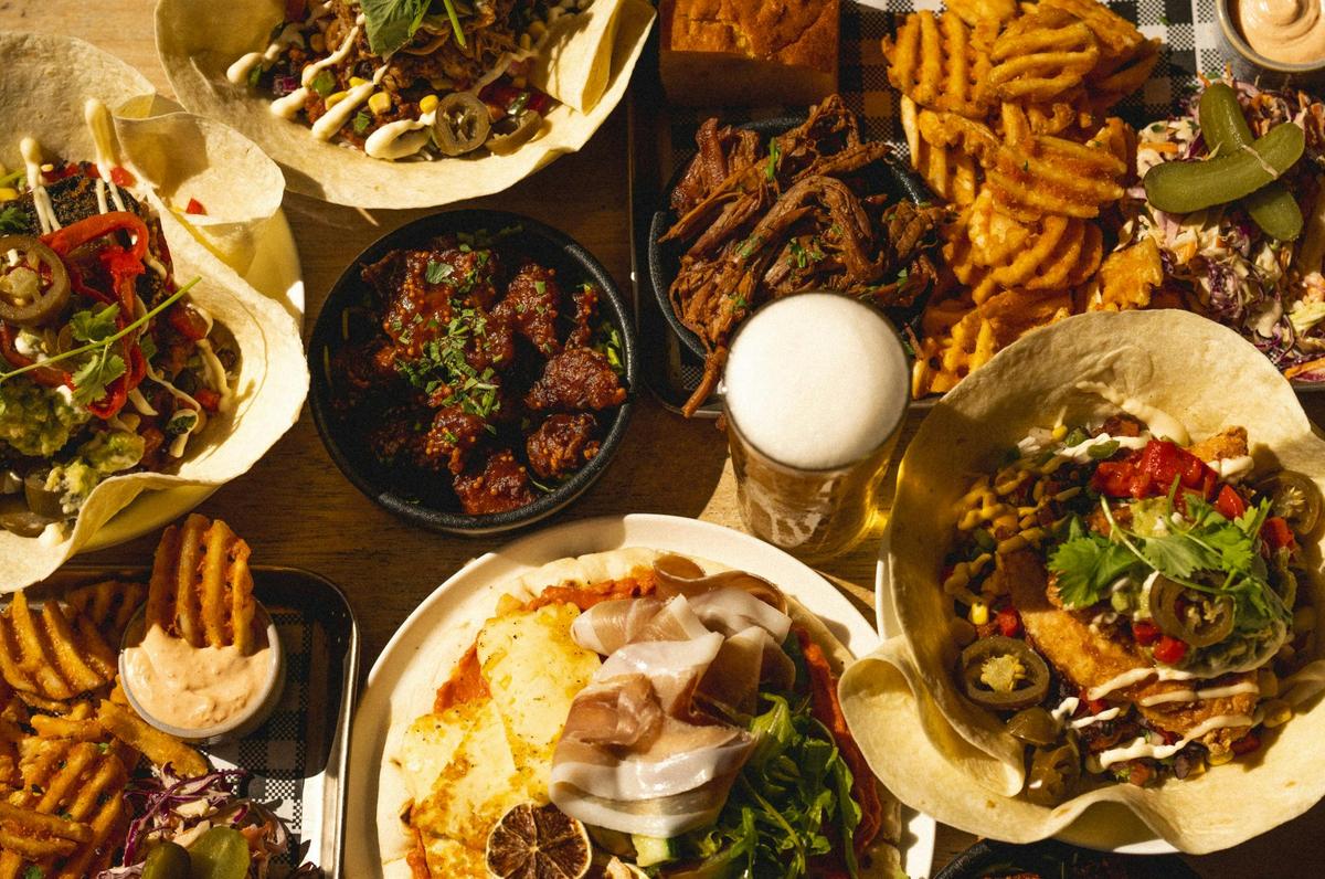 Spread of burrito bowls and share plates with beer