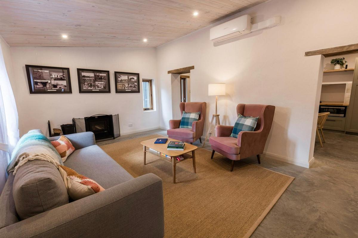 Lounge room showing a two seater couch, two armchairs and a combustion heater