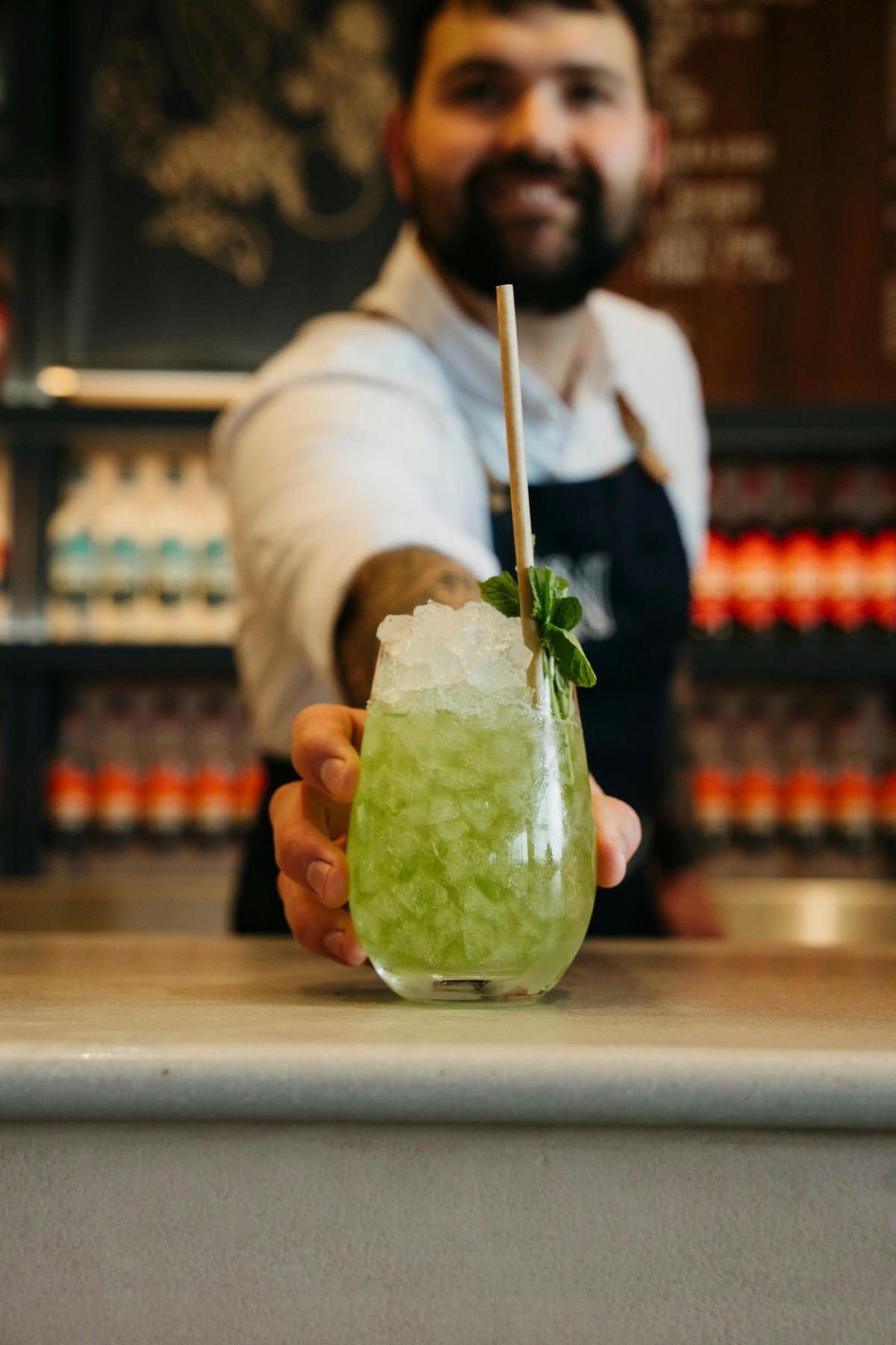 green cocktail served on crushed ice with mint sprig and straw