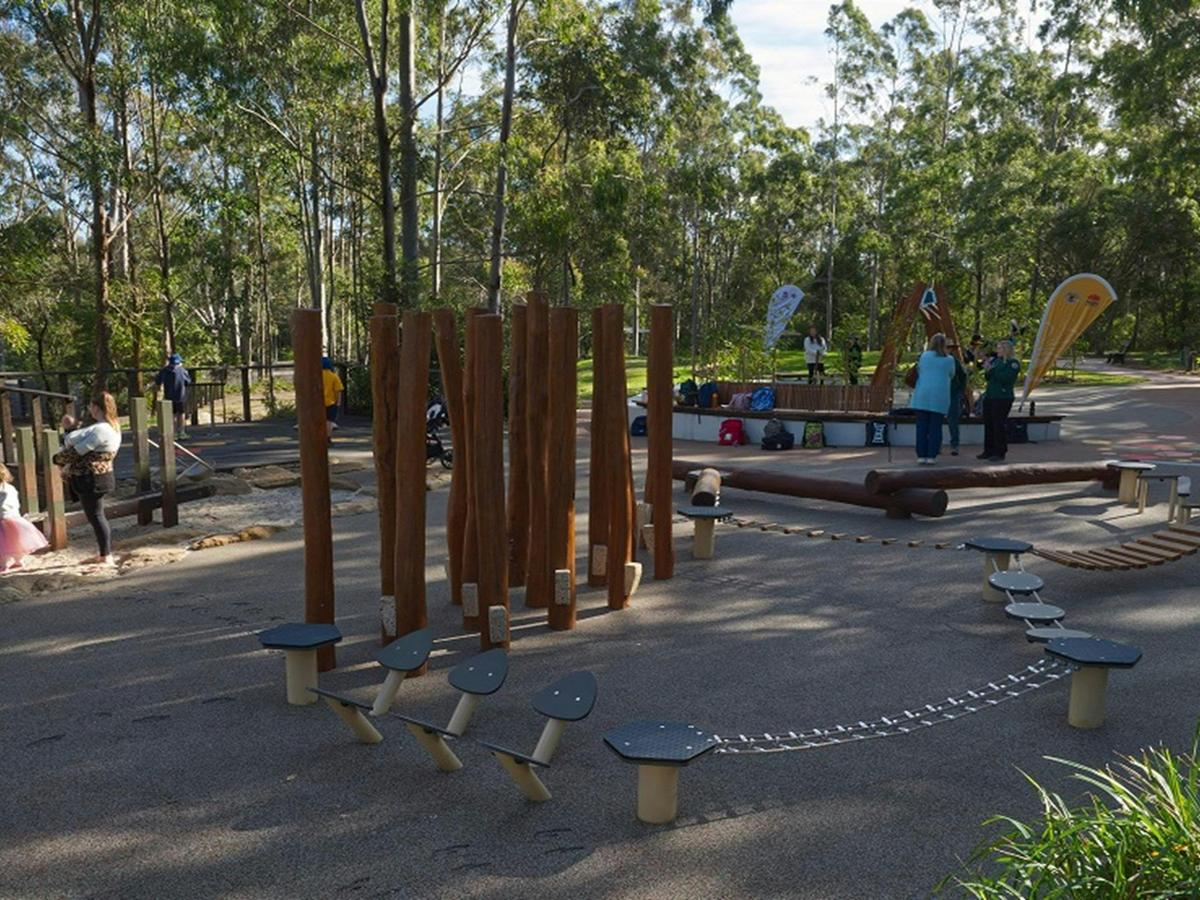 A wider view of the playground, with people and children playing, Village Green picnic area and