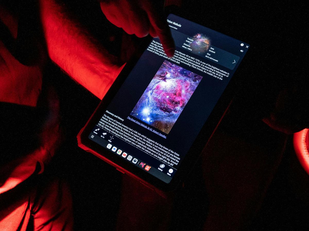 Exploring the Orion Nebula via the Sky Safari app under astronomy-friendly red lights.