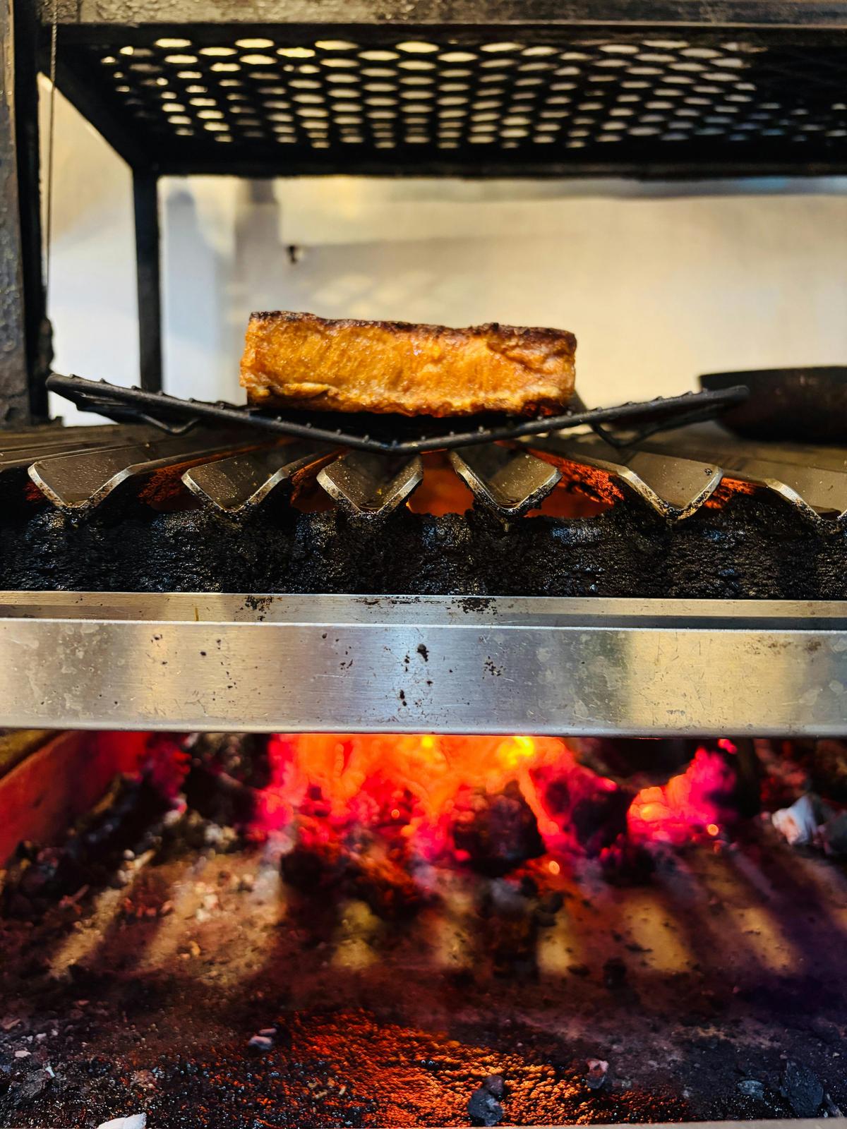 Chef cooking over an open red gum wood fire grill at The Banksia Tree Cafe, Port Adelaide