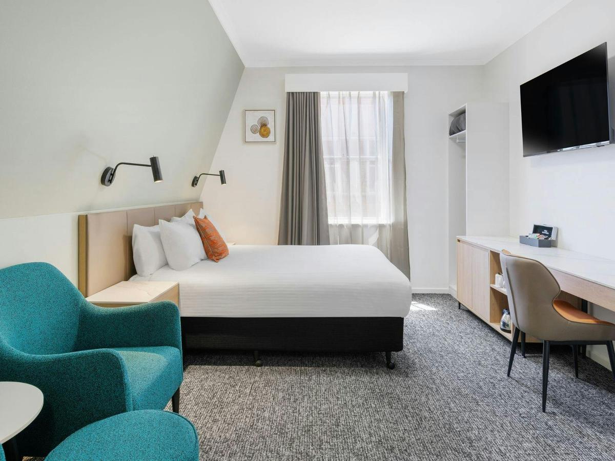 Modern Queen Room with a plush bed, warm lighting, and stylish décor at The Chancellor on Currie.