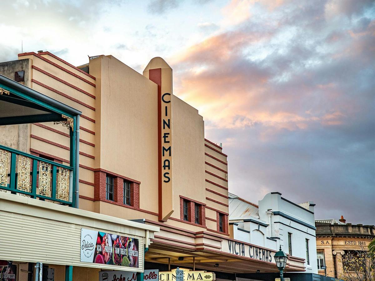 The bold art deco facade of Victa Cinema set against a cloudy sunset.