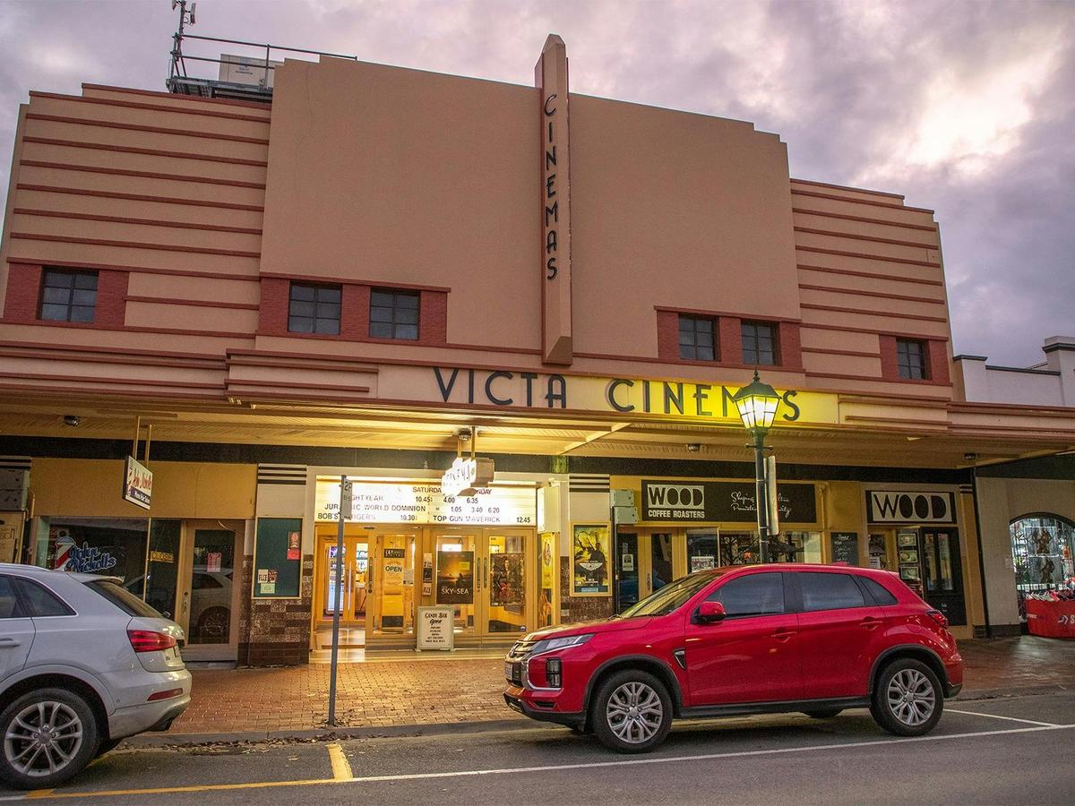 A wide view of the cinema from street level with a cloudy sunset background.