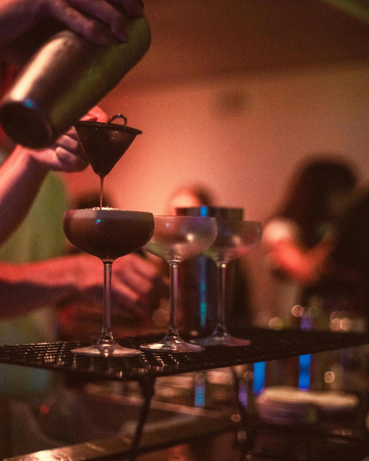 cocktails being poured over the bar