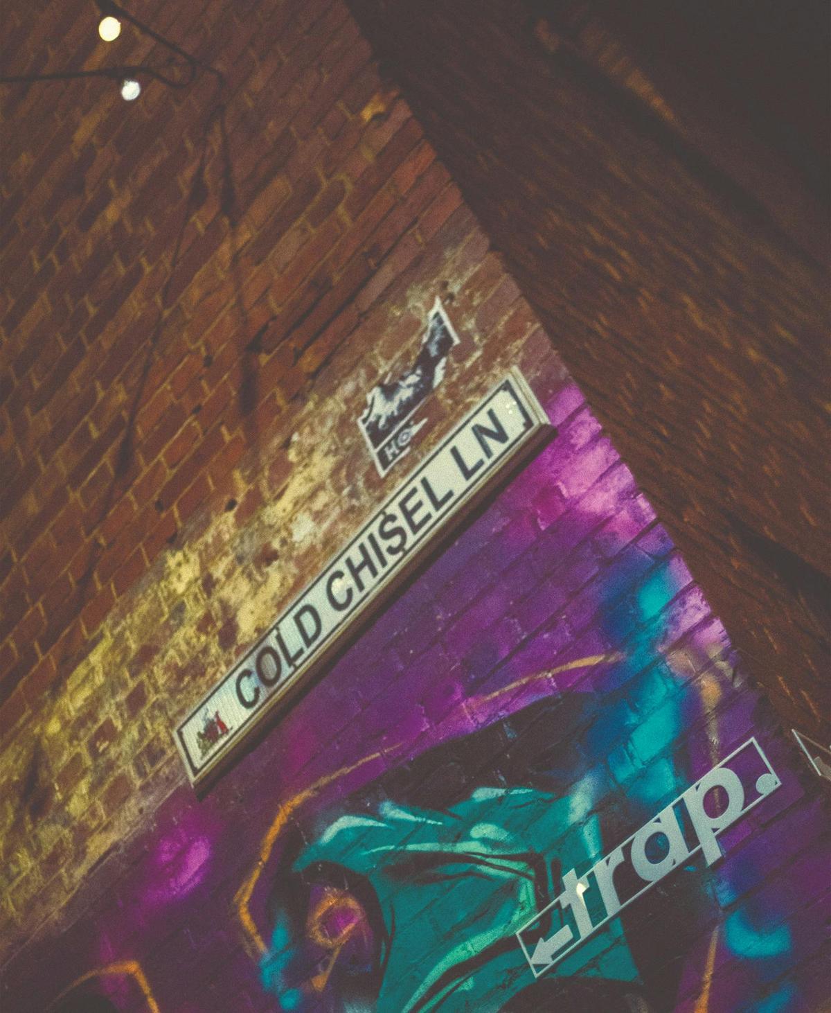 close up external shot displaying a street signed titled 'cold chisel lane' above an arrow of a shop